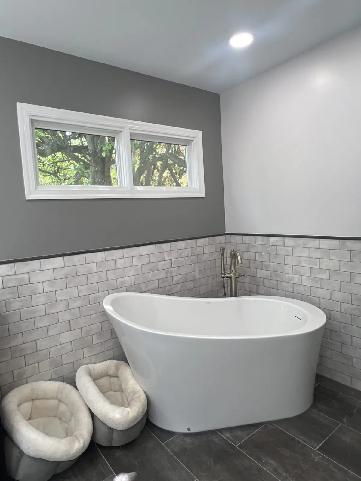 Freestanding tub under a window with subway tile