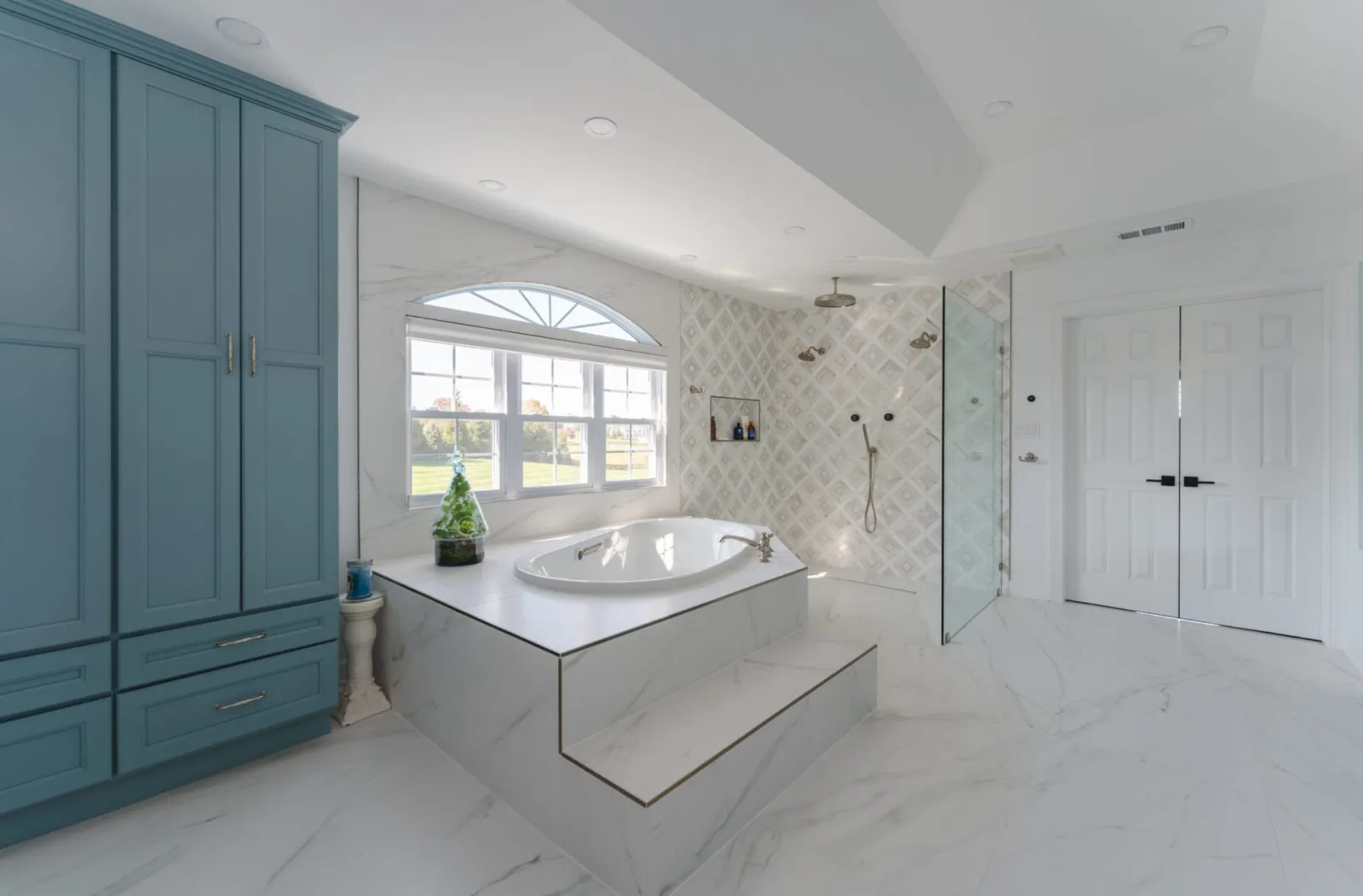 Soaking tub on a marble platform with a walk-in shower